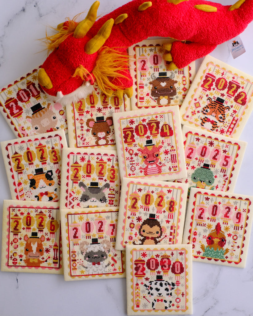 Lunar New Year Cross Stitch Pattern A pile of year flat folds with all 13 animals of the Zodiac with a Jellycat stuffed dragon