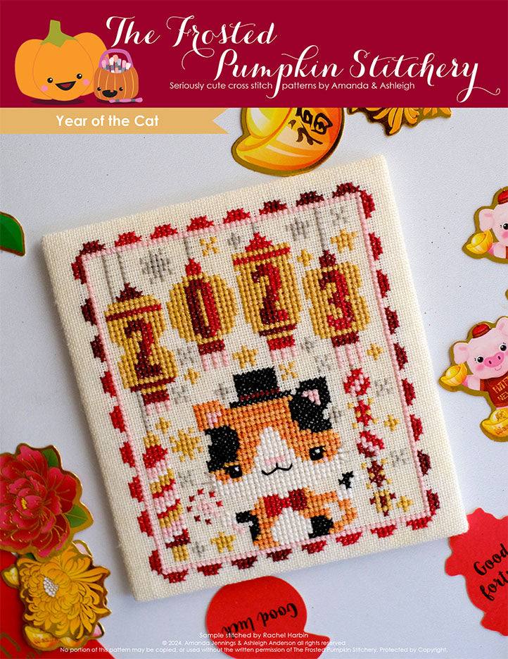 Year of The Cat Cross Stitch Pattern A calico cat is wearing a top hat and surrounded by hanging yellow gold lanterns that spell out 2023